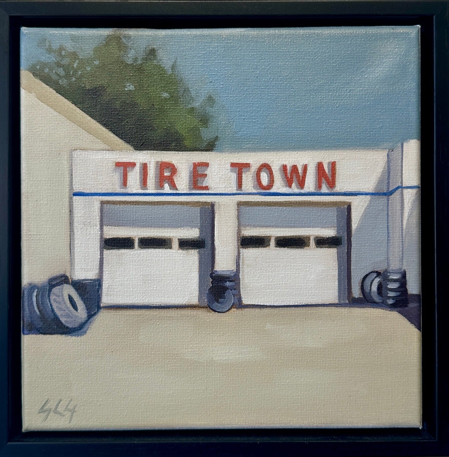 Framed artwork of a building with 'Tire Town' sign on a white wall